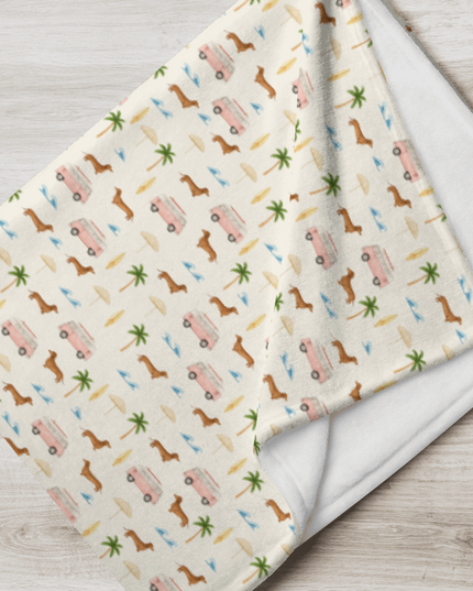 Folded dachshund blanket with beach print featuring wiener dogs, vans, and palm trees