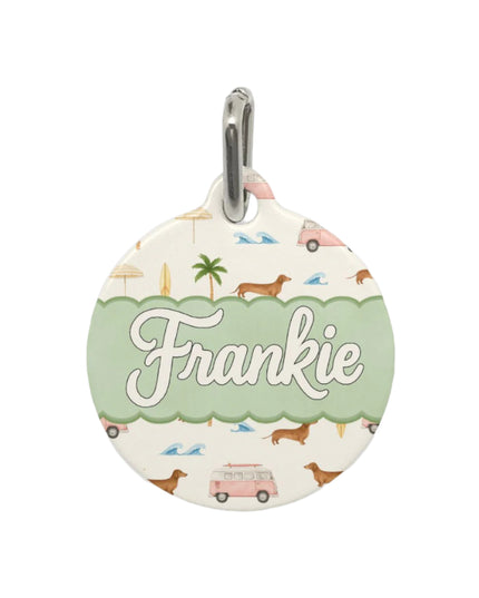 Round pet tag with 'Frankie' on a cream background featuring dachshunds, palm trees, pink vans and beach umbrellas